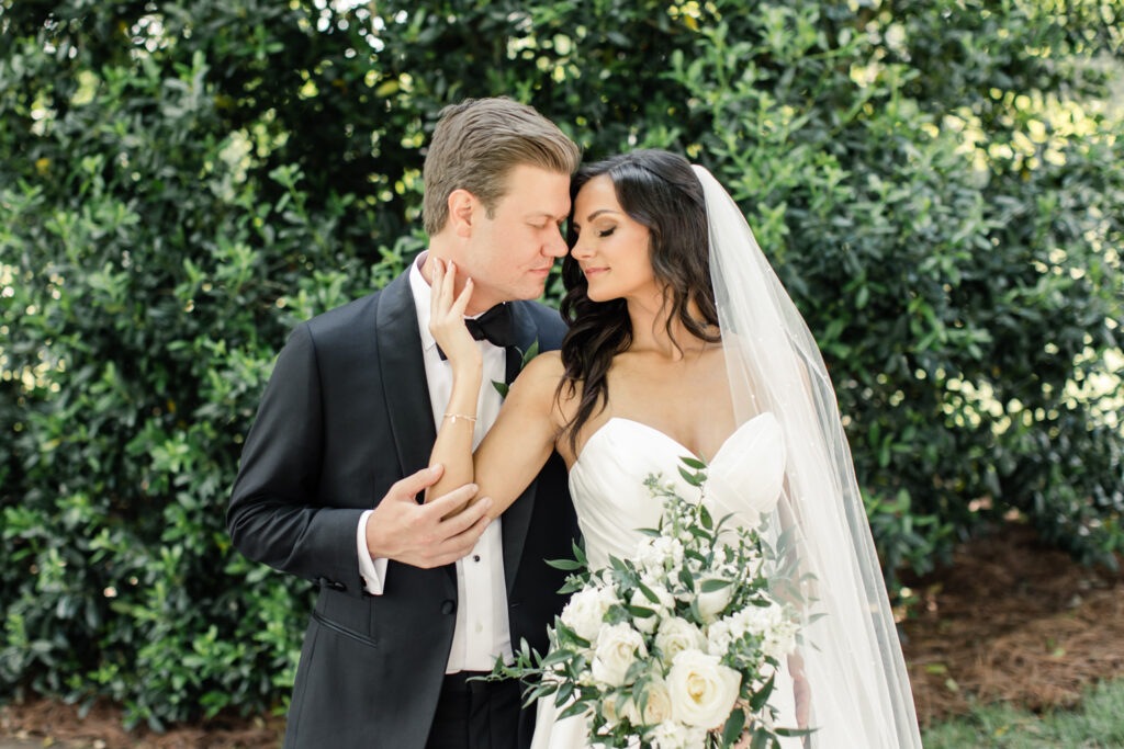 Bride, in white strapless dress, nose to nose with groom, in black suit, at Long View Country Club Wedding Venue Charlotte NC