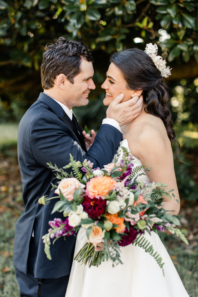 Bride with brown hair in a white strapless dress and crown smiling at groom with brown hair in a navy suit at The Palmer Building Wedding Venue. Photographed by Charlotte Wedding photographer, Stephanie Bailey.