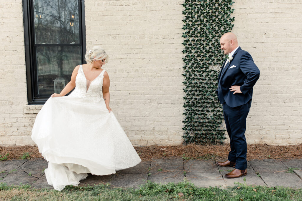 Bride with blonde hair in a white lace dress seeing her groom, in a navy suit for the first time at The Bottle Factory Wedding Venue. Photographed by Charlotte wedding photographer.
