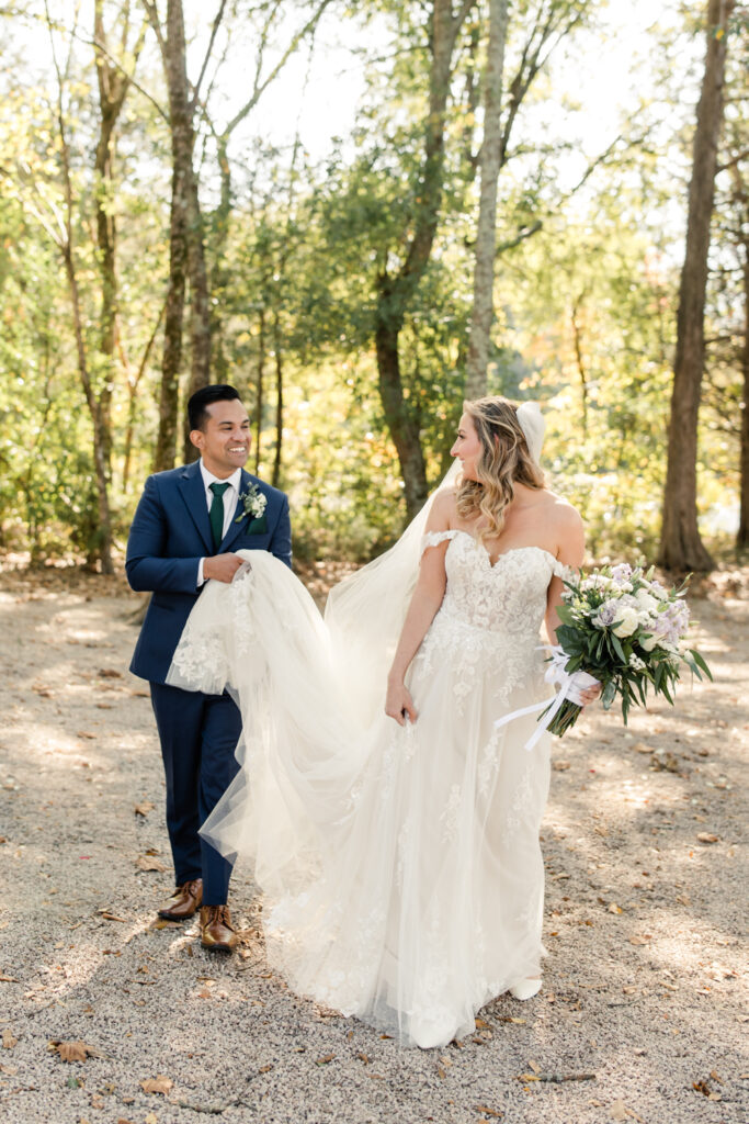 Bride with long blonde hair in a white lace dress hugging groom in blue suit at Riverwood Manor Wedding Venue. Photographed by Charlotte wedding photographer, Stephanie Bailey.