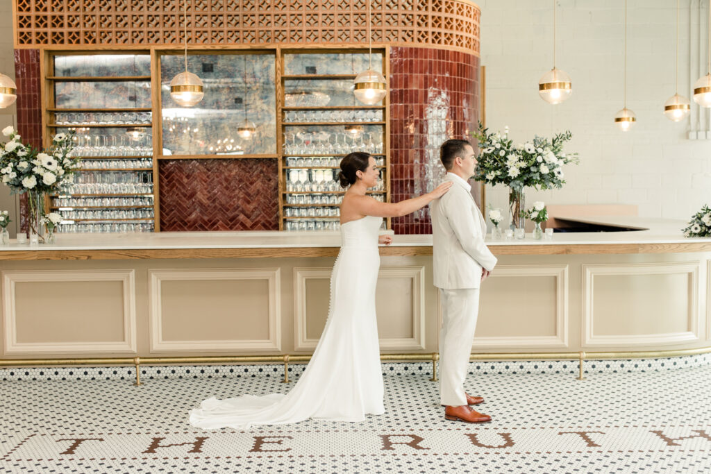 Bride, in white strapless dress, seeing her groom, in tan suit, for the first time at The Ruth wedding venue in Charlotte NC. Photographed by Charlotte Wedding Photographer.